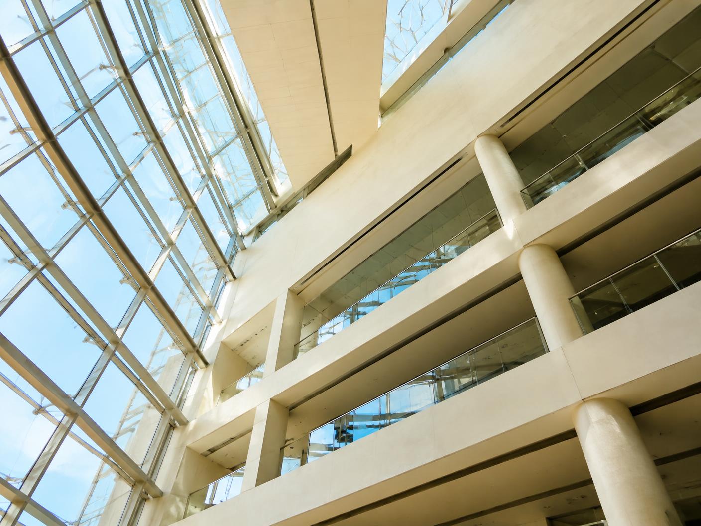 Geometric interior of a modern glass and concrete atrium seen from below